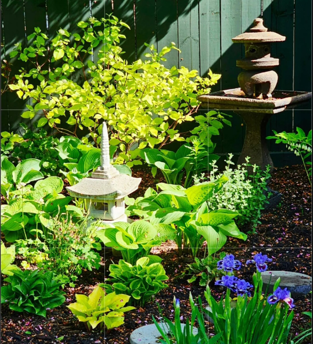 Gartenskulpturen um hellgrüne Laubpflanzen